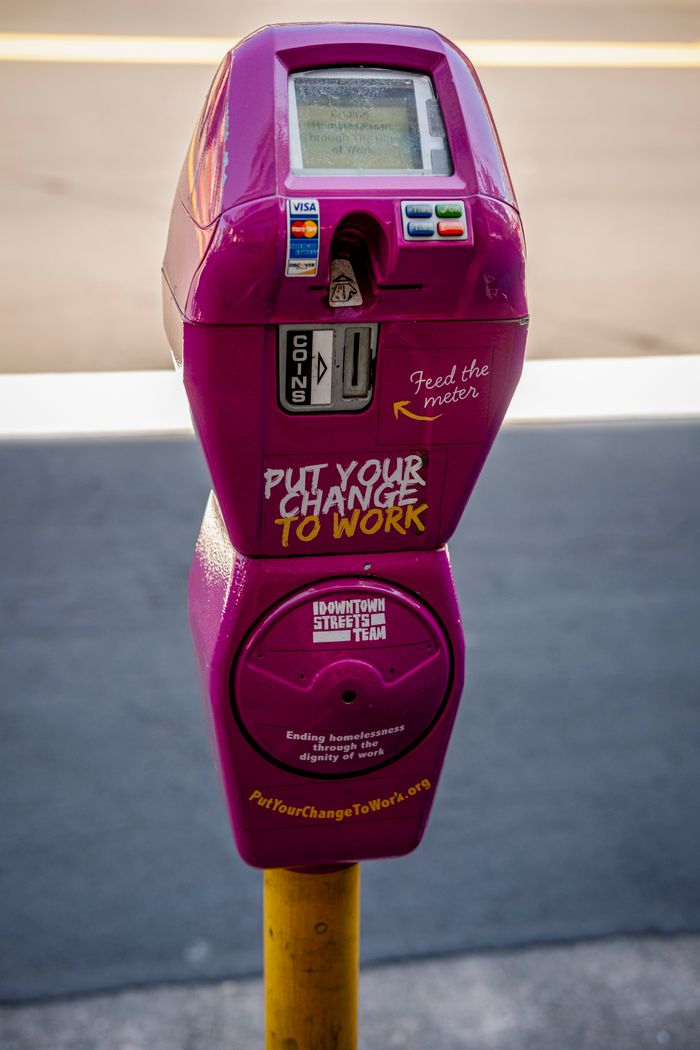 Bright pink parking meter with charity message for homelessness support.