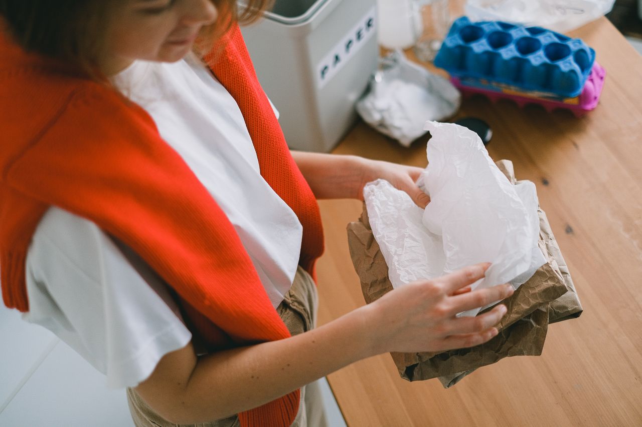 Crop anonymous female in casual clothes sorting out rubbish while standing in light apartment in daytime